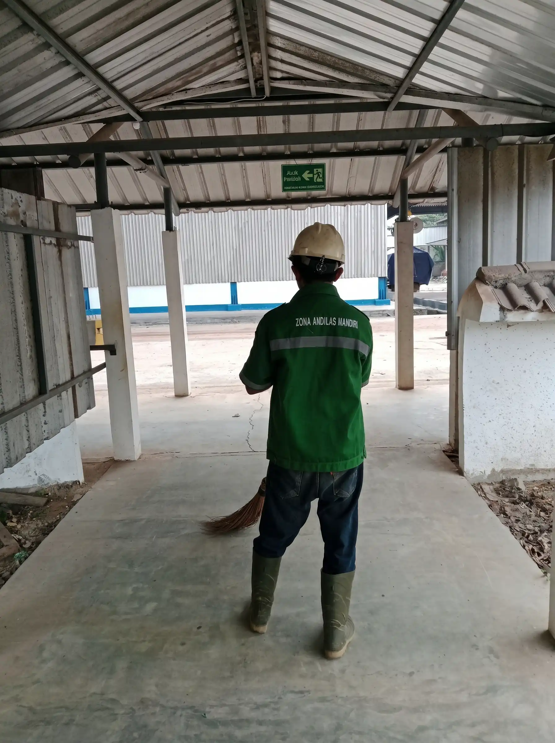 Pekerja cleaning service ZAM Lampung sedang menyapu area kerja luar ruangan